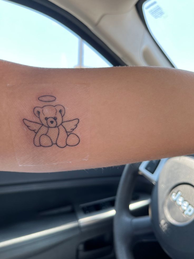 a small teddy bear tattoo on the arm