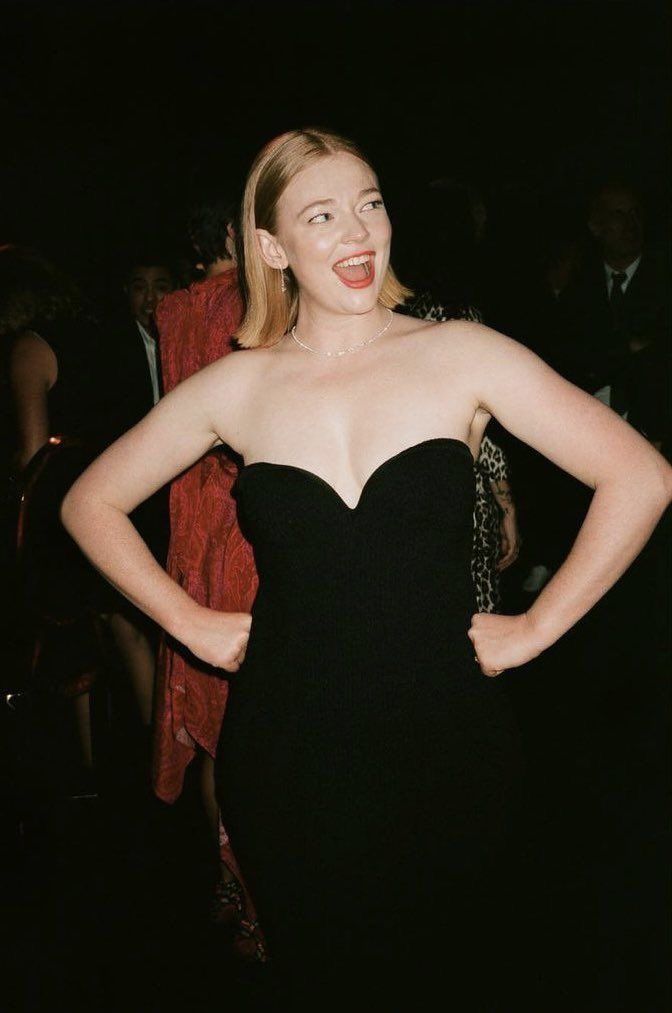 a woman in a black dress standing with her hands on her hips