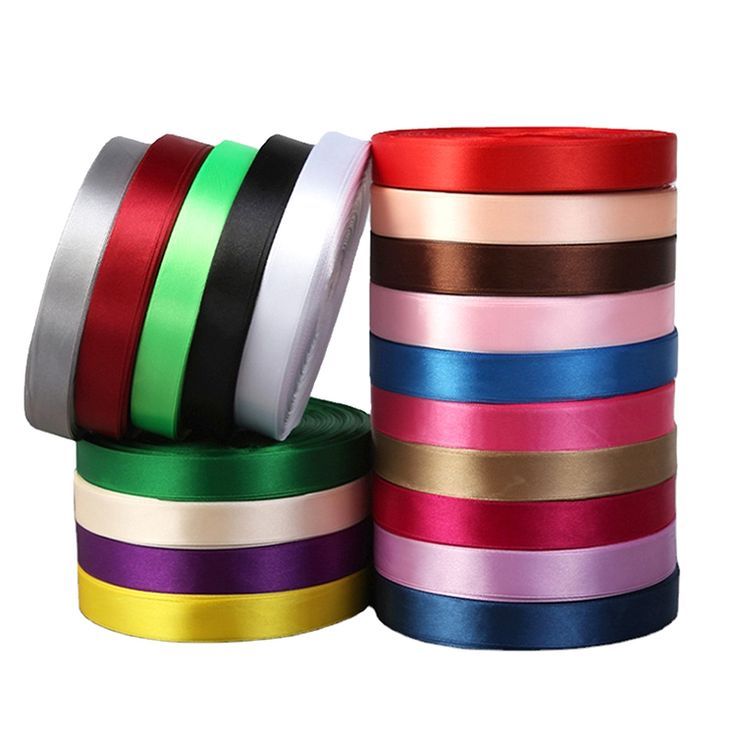 various colors of satin ribbon are stacked on top of each other, with one roll in the middle