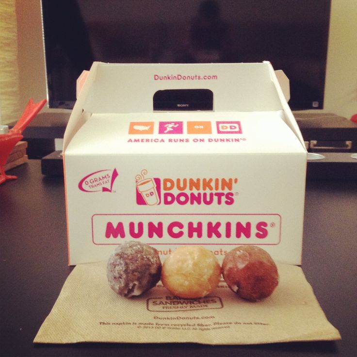 three doughnuts sitting in front of a dunkin donuts box on a table