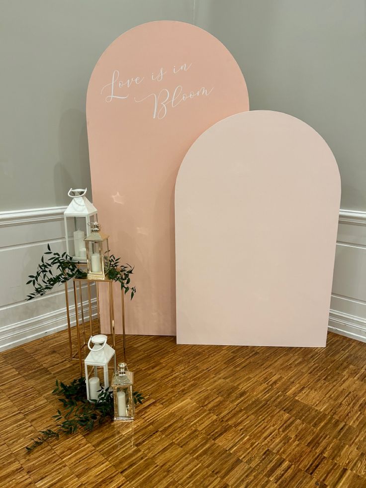 a couple of white lanterns sitting on top of a wooden floor next to a pink sign