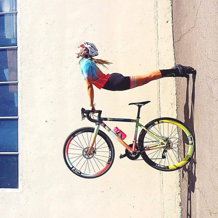 a woman is doing a trick on her bike while hanging off the side of a building