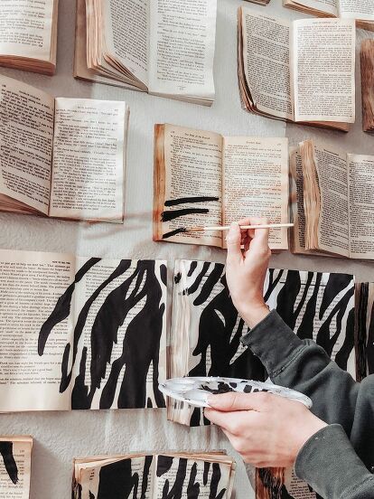 a person holding a paintbrush in front of an open book wall with zebra prints on it