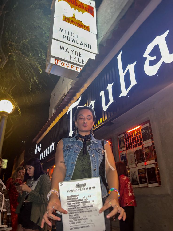 a woman standing in front of a store holding a sign