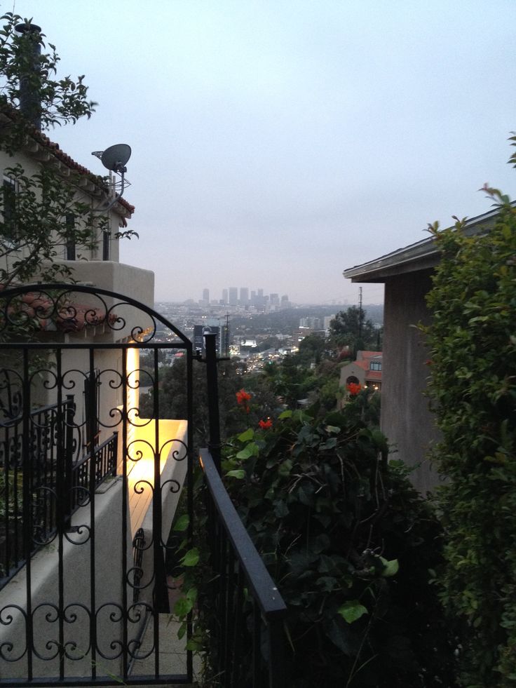 an iron gate is open on the side of a house with city in the background