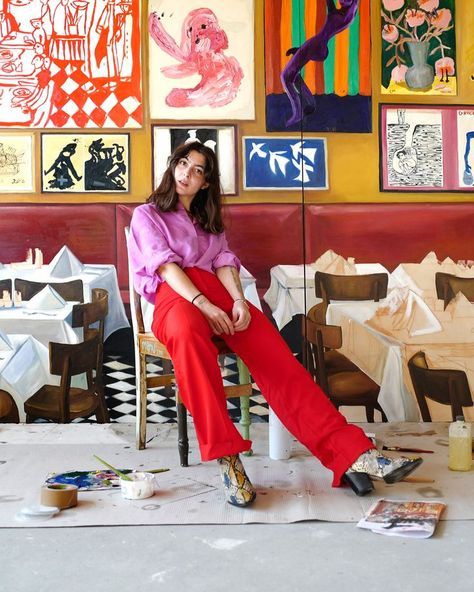 a woman sitting on a chair in front of paintings