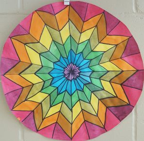 a colorful circular stained glass piece hanging on a white brick wall in front of a door