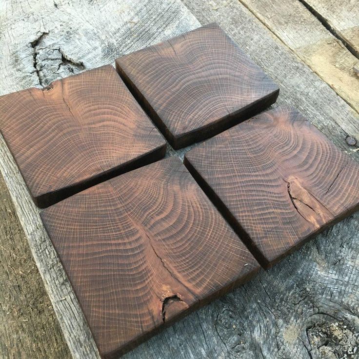 four square pieces of wood sitting on top of a wooden table next to each other