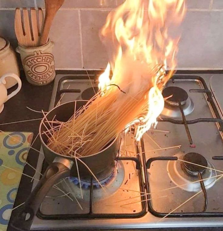 a pot on top of a stove with spaghetti in it's burner and flames coming out