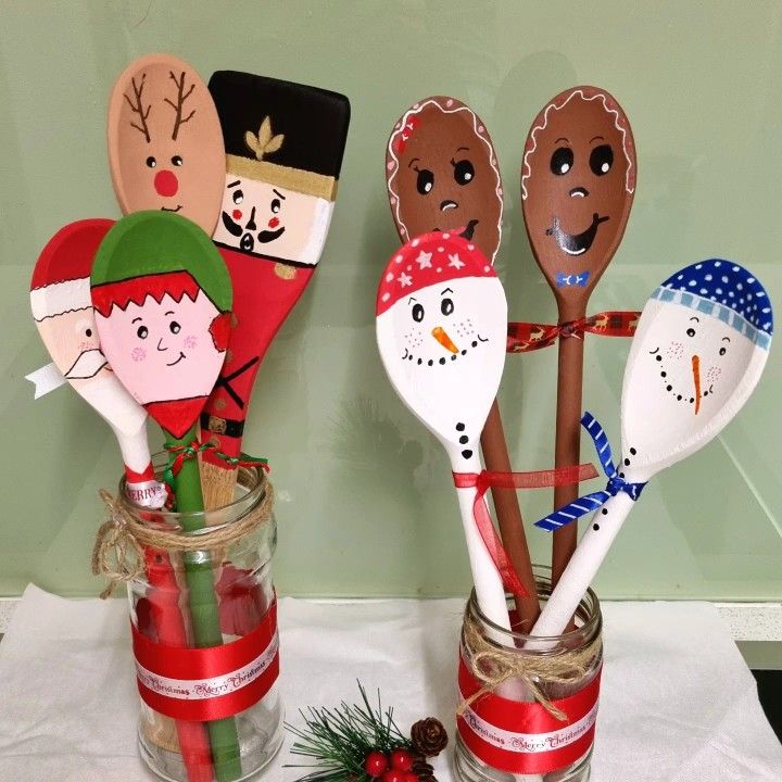 four wooden spoons decorated with christmas characters in mason jars