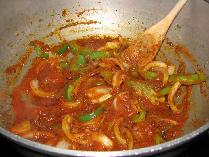 the food is being cooked in the pan on the stove top with a wooden spoon