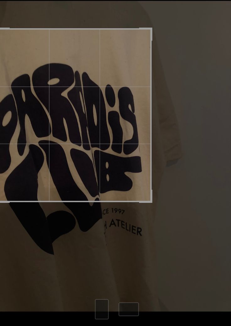 a t - shirt with the words paris on it is hanging up in front of a wall