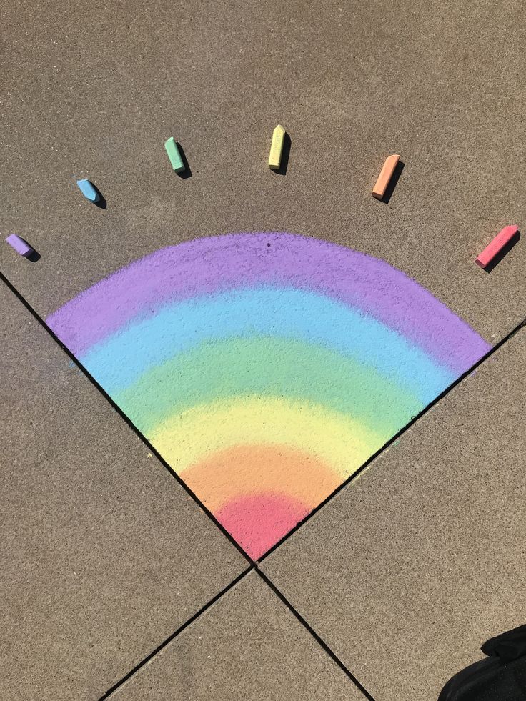 colored crayons are arranged on the ground in front of a rainbow - shaped area