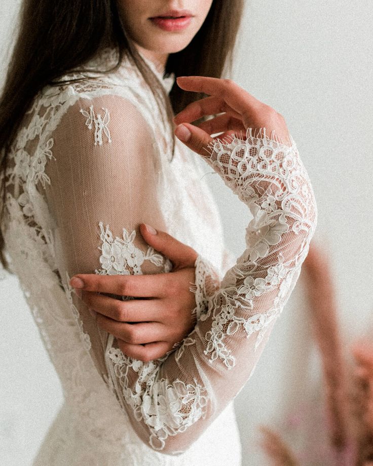 a woman in a white dress is holding her hands on her chest and posing for the camera