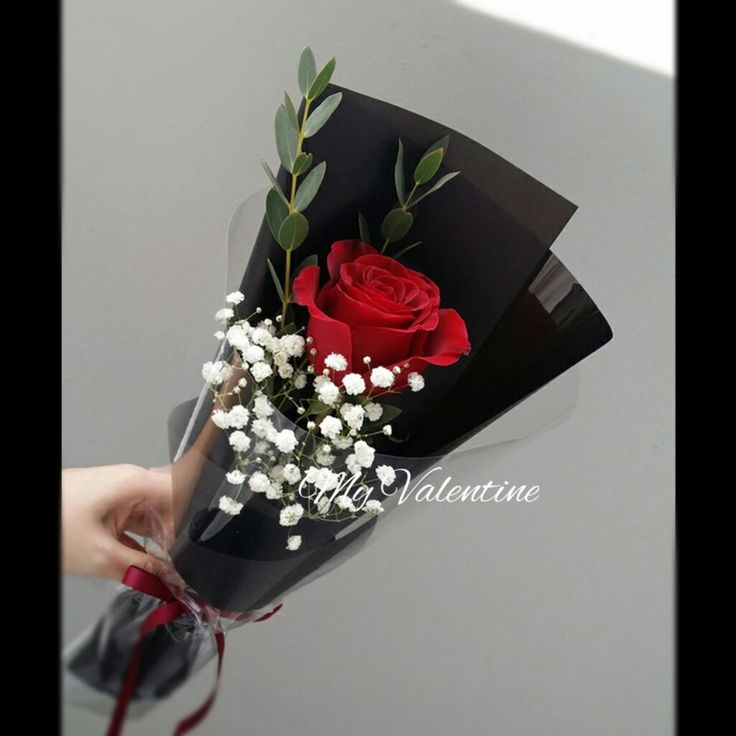 a person holding a bouquet of flowers with red roses and baby's breath in it