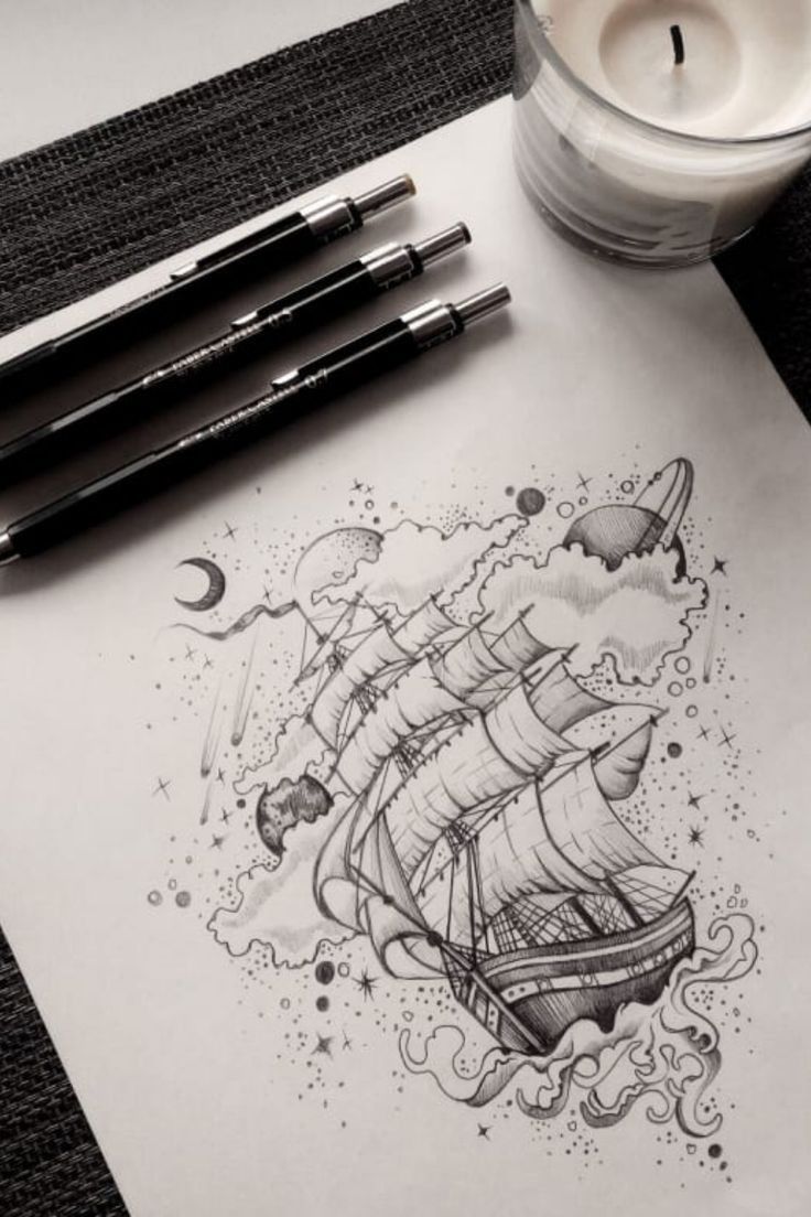 a drawing of a ship on paper next to two candles