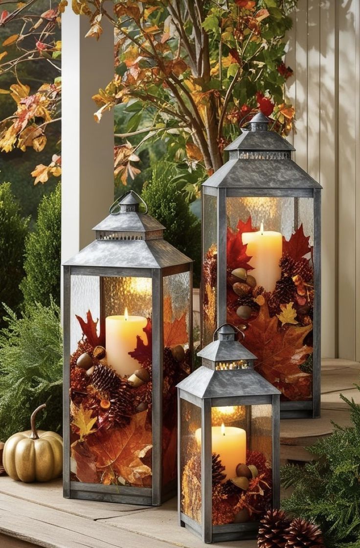 two lanterns sitting on top of a wooden porch next to trees and leaves with candles in them