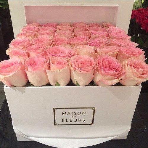 pink roses are in a white box on a black counter top with the name maison fleurrs