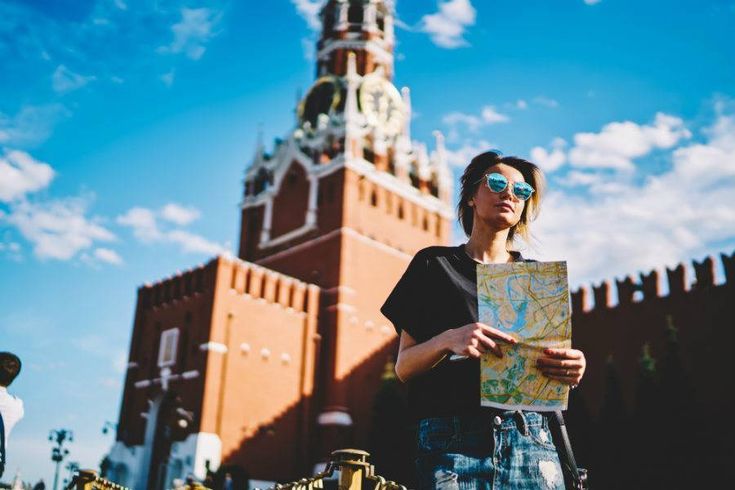 a woman standing in front of a tall building holding a map