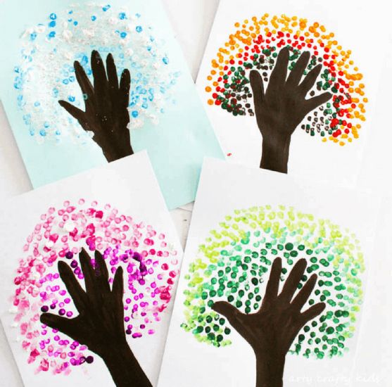 three handprinted cards with different colors of hands on them, and one is holding a tree