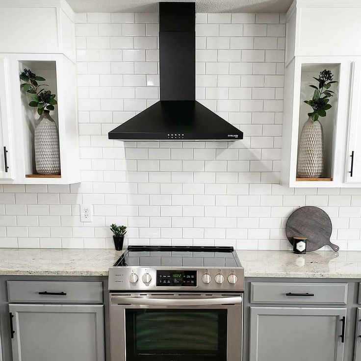 a stove top oven sitting inside of a kitchen next to white cupboards and drawers