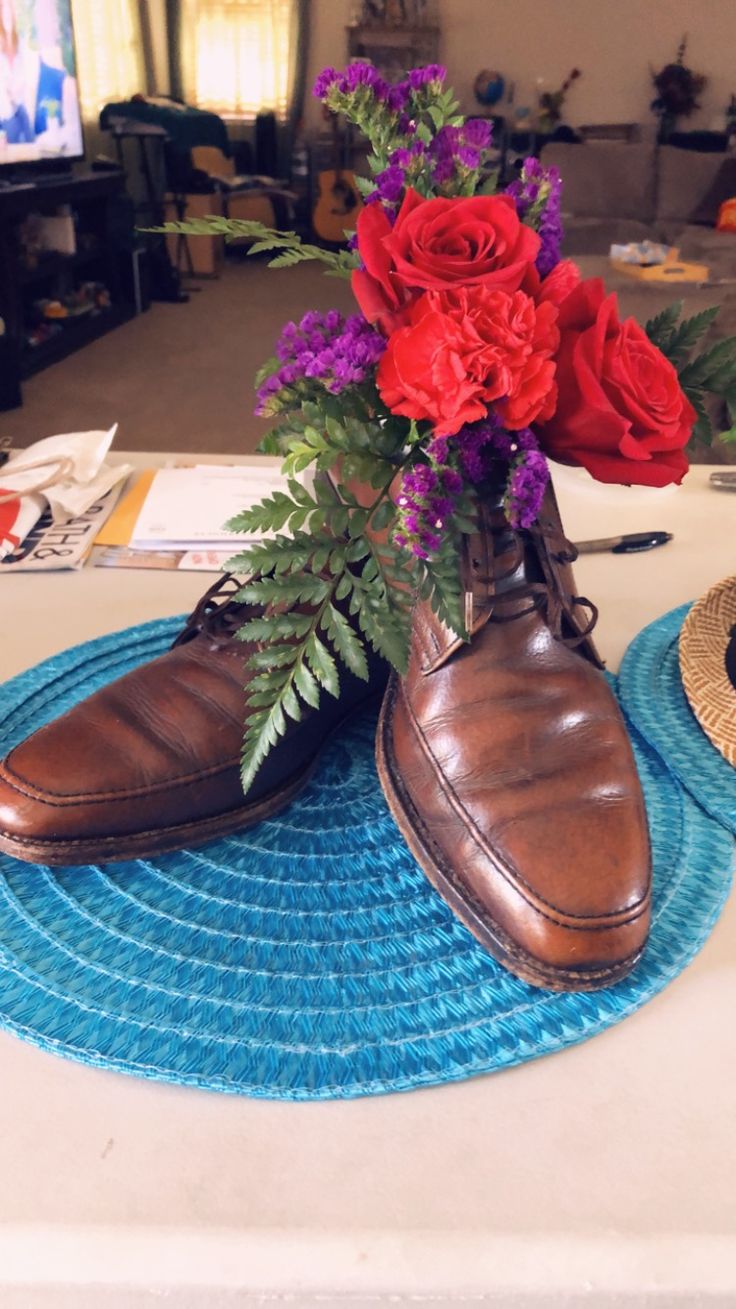 a pair of brown shoes sitting on top of a blue mat next to red flowers