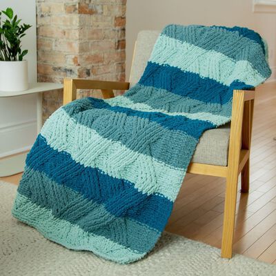 a blue and green blanket sitting on top of a wooden chair