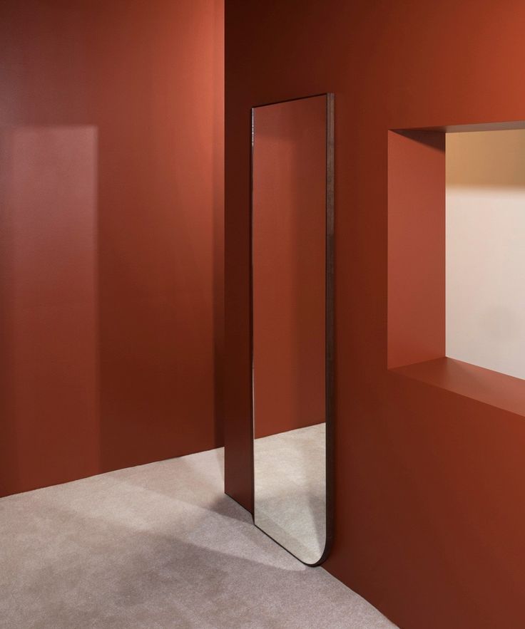 an empty room with red walls and a large mirror on the wall next to it