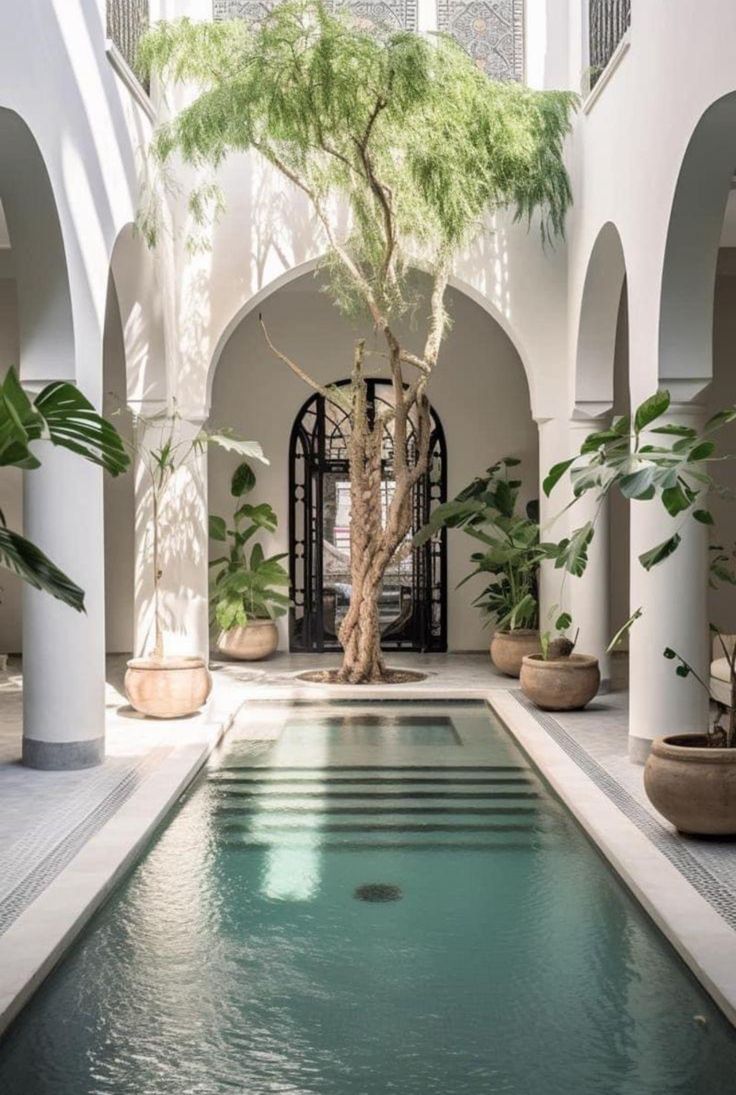 an indoor swimming pool surrounded by potted plants and arches with arched doorways on either side