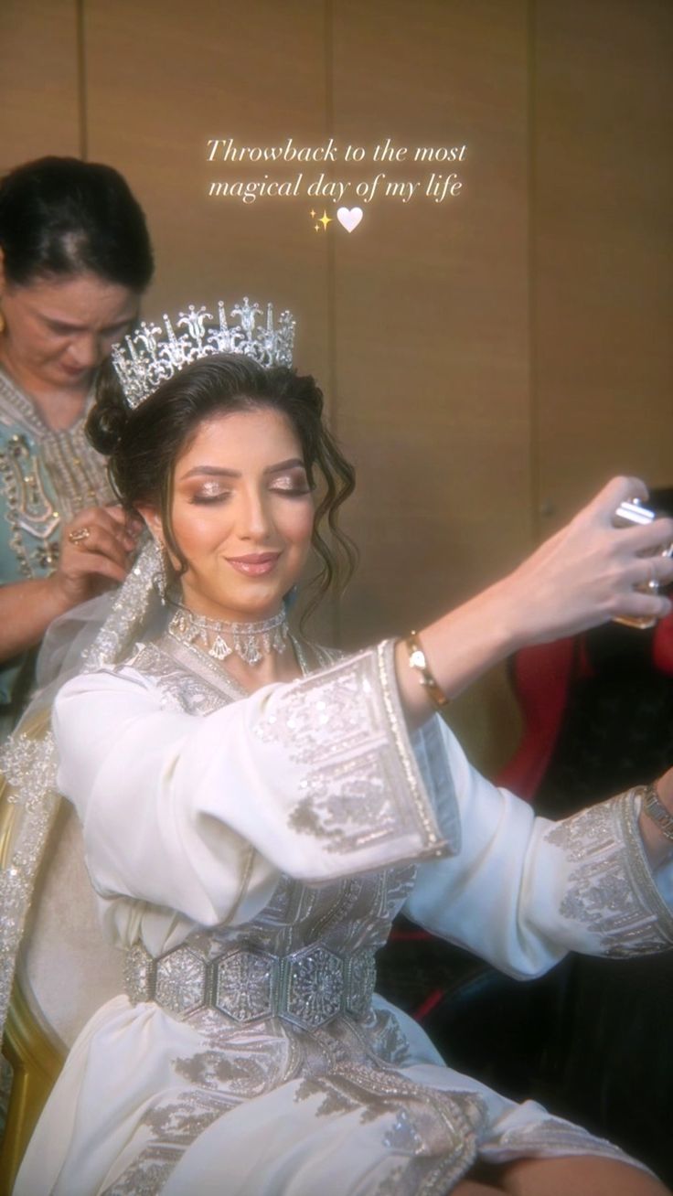 a woman is getting her hair done by a man wearing a tiara and holding a cell phone