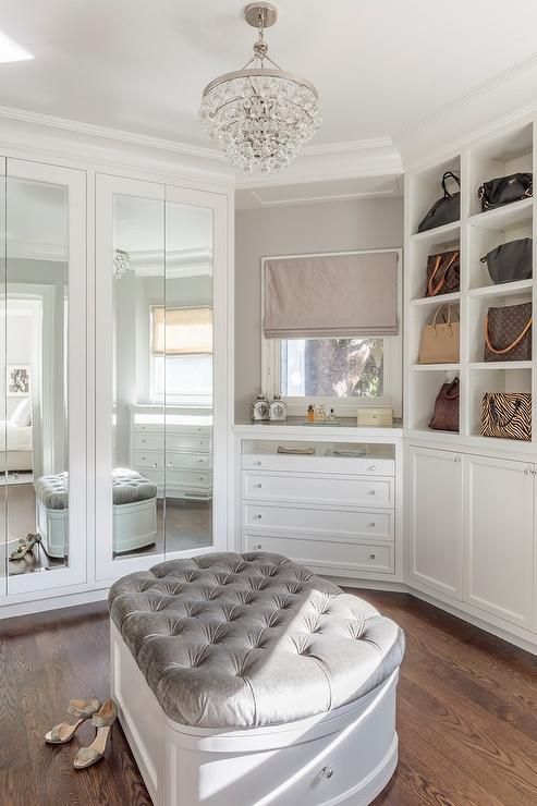 a bedroom with white walls and wooden flooring has a round ottoman in the middle