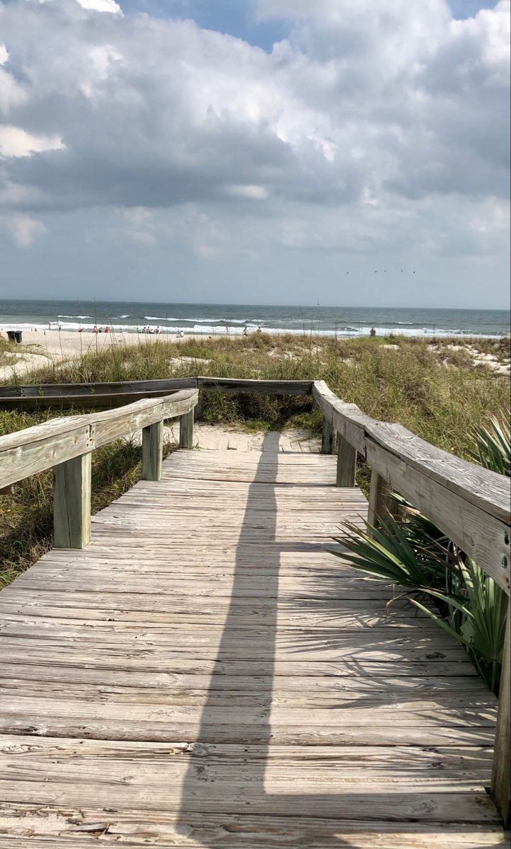 a wooden walkway leading to the beach on a cloudy day