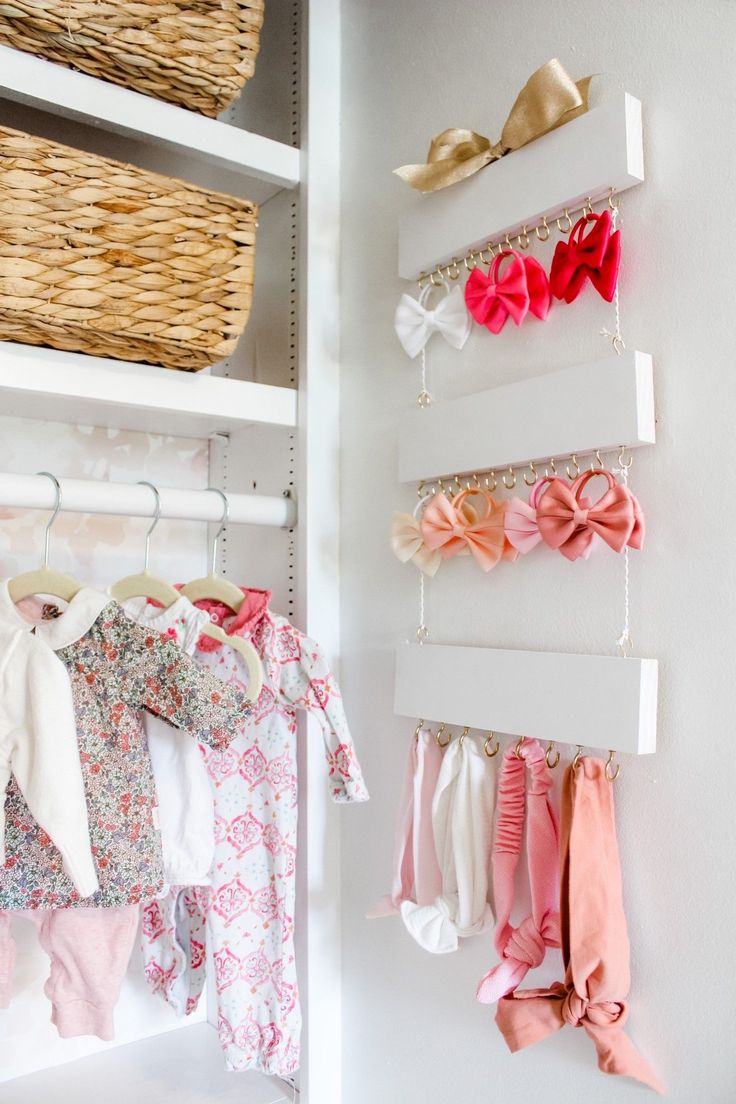 baby clothes are hanging on the wall next to shelves with baskets and bow ties in them