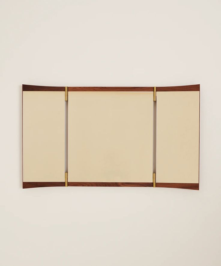 a white wall mounted with three brown wooden pieces on it's sides and two mirrors above them