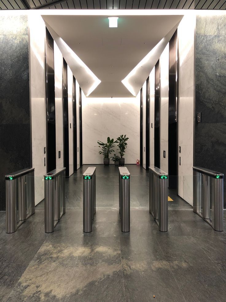 an empty hallway with metal trash cans and plant in the center, surrounded by white walls