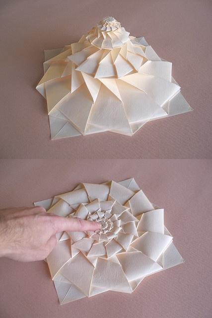 two pieces of folded paper being held up by someone's hand with their fingers