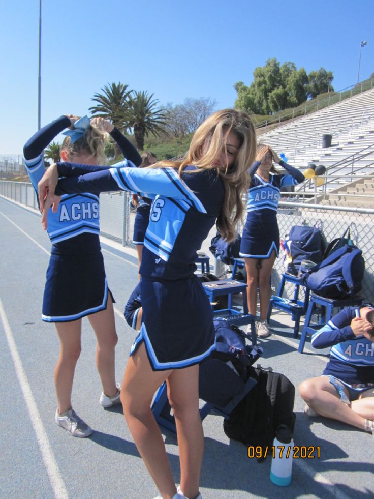 the cheerleaders are getting ready to perform on the sidelines in their uniforms