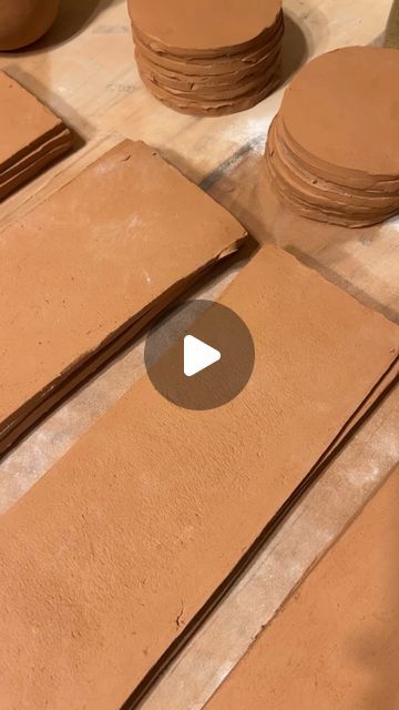 several pieces of brown clay sitting on top of a table next to stacks of discs