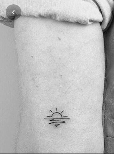 a black and white photo of a person with a sun tattoo on their arm