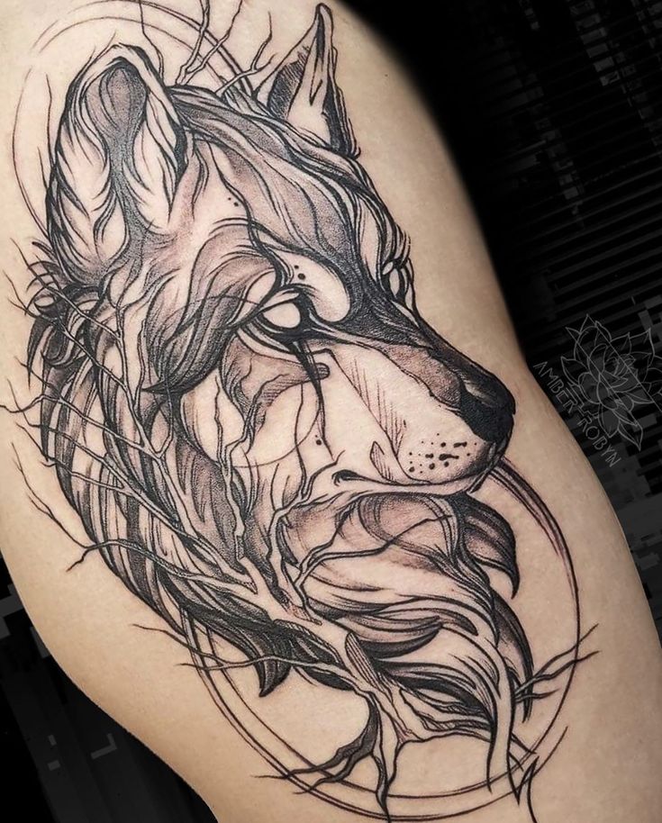 a black and white tattoo design of a wolf's head on the thigh,