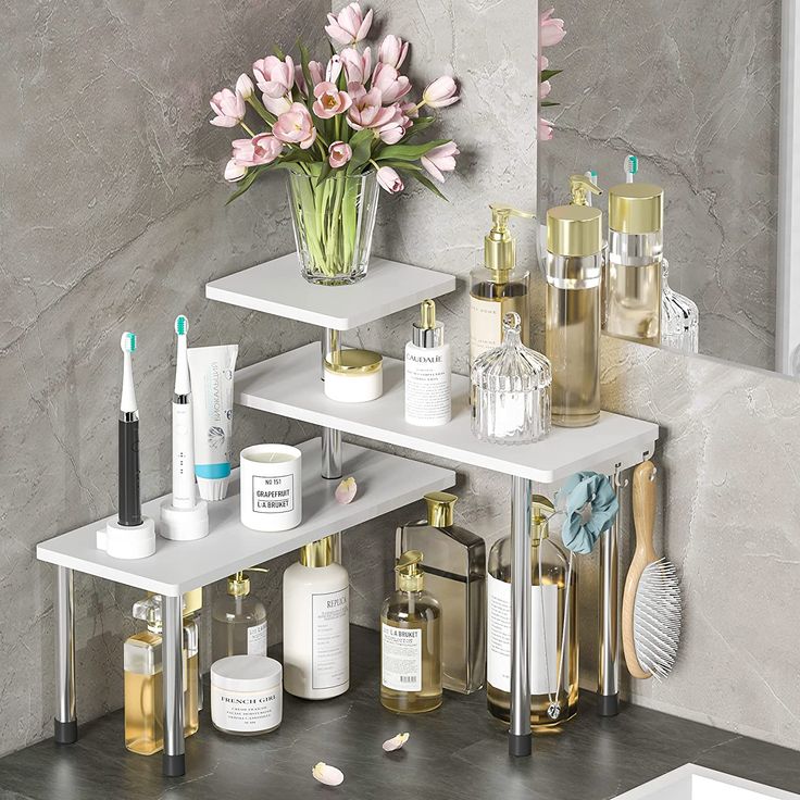 three tiered shelf with various beauty products and flowers in vase next to mirror on wall