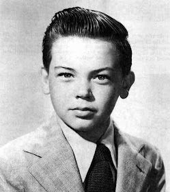 an old photo of a young boy wearing a suit and tie