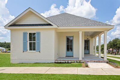 a small white house with blue shutters on the front door and windows in the back