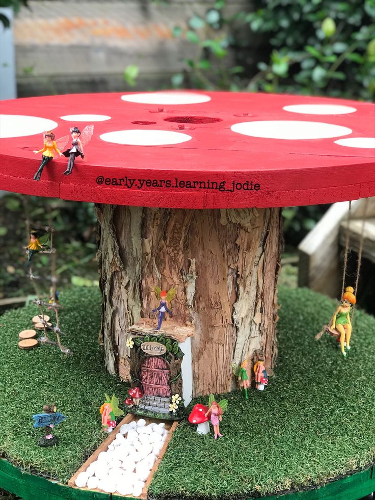 a table made out of a tree stump with little fairy figurines on it