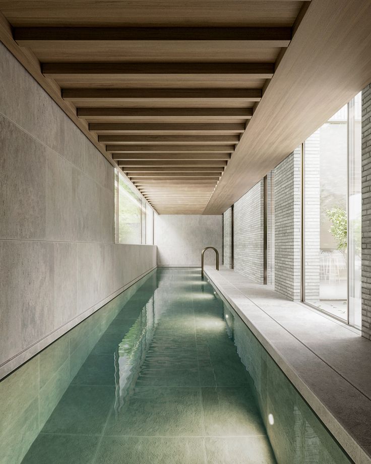 an indoor swimming pool surrounded by concrete walls and flooring with water running through it