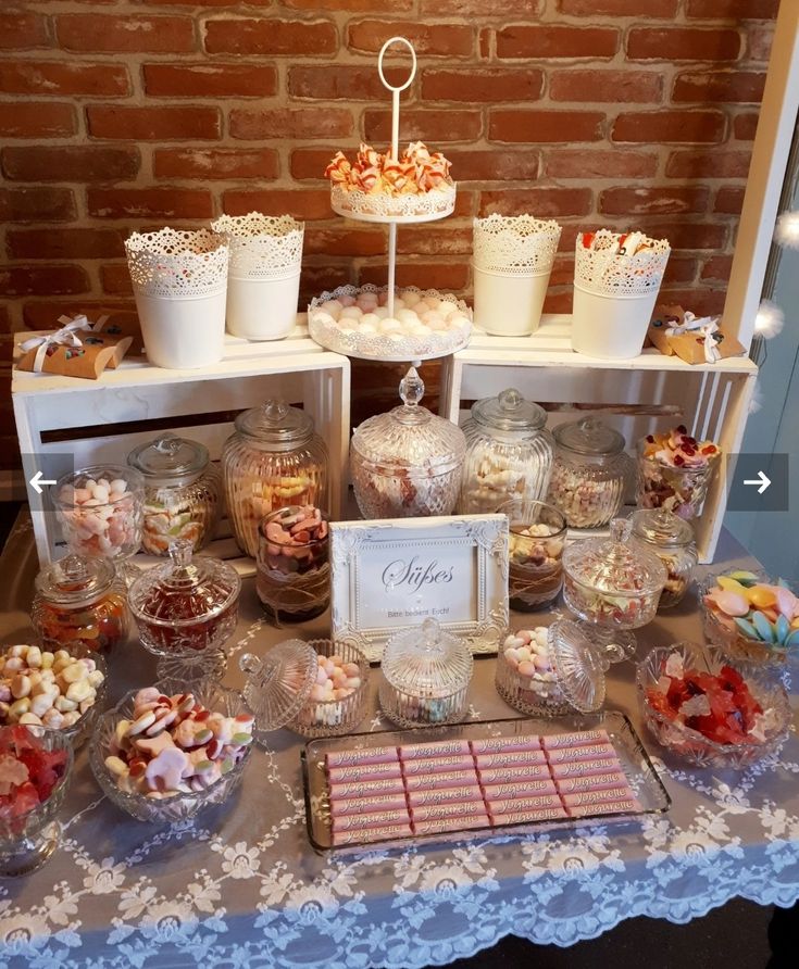 a table topped with lots of candy and candies next to a red brick wall