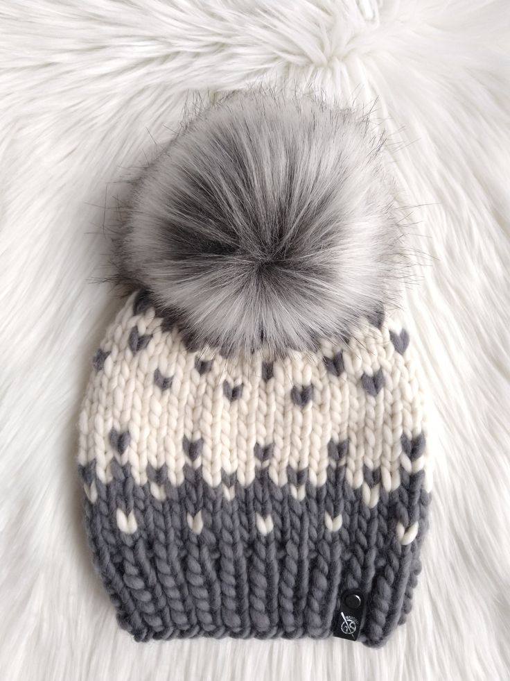 a gray and white knitted hat with a pom - pom on top