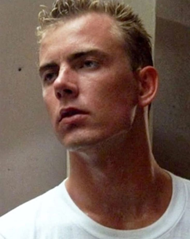 a man in a white t - shirt is looking at the camera with an intense look on his face