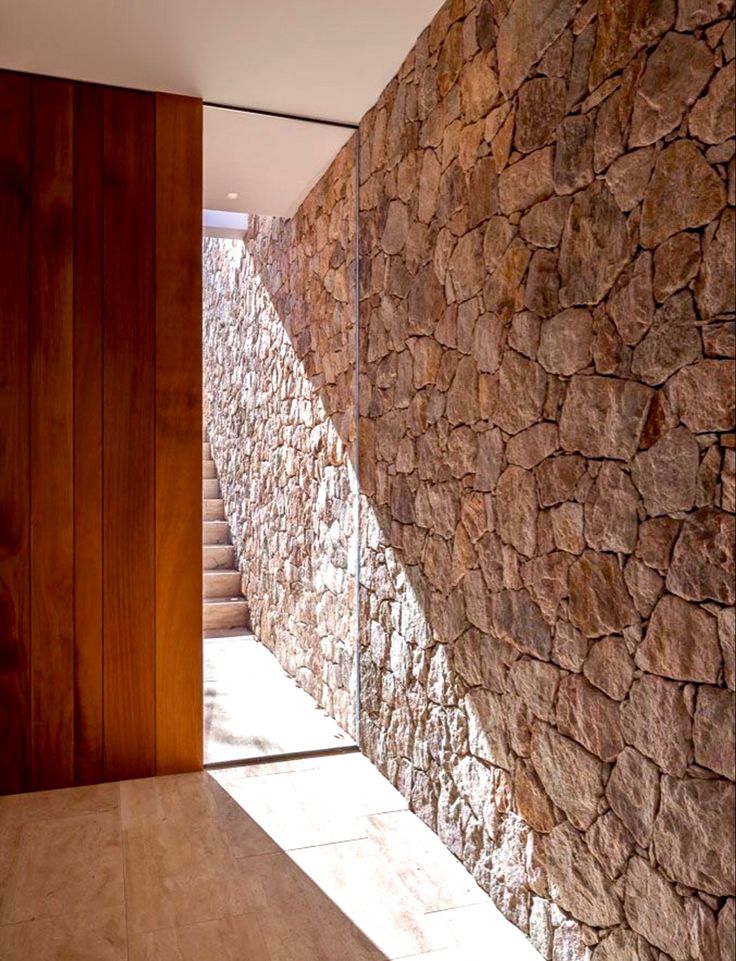 a stone wall next to a wooden door in a room with wood floors and walls