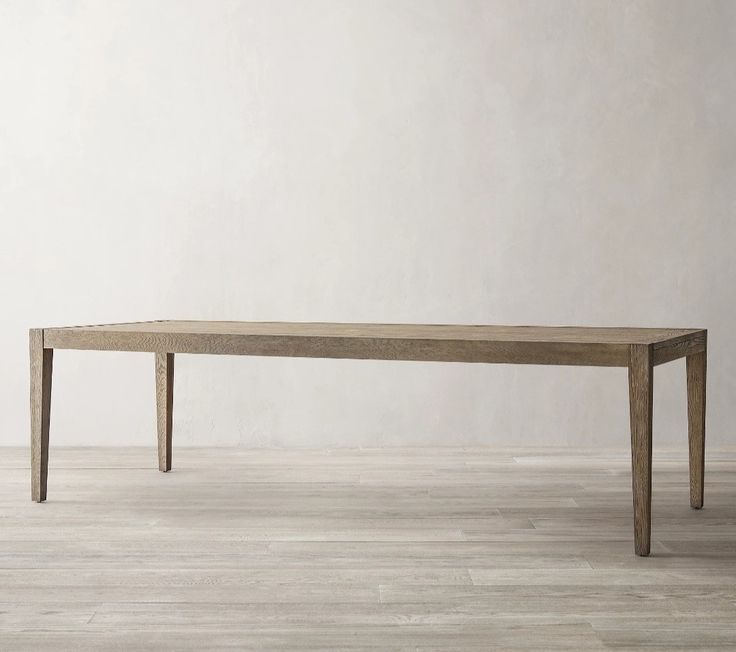 a wooden table sitting on top of a hard wood floor next to a white wall